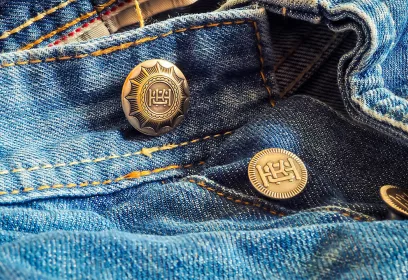 Ausschnitt einer blauen Jeans mit Knopfleiste