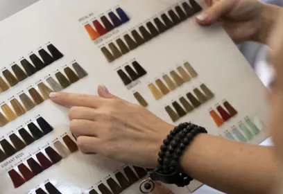 Musterübersicht von verschiedenfarbigen Kosmetikpinseln und einer Frauenhand, die auf einem Farbton zeigt.